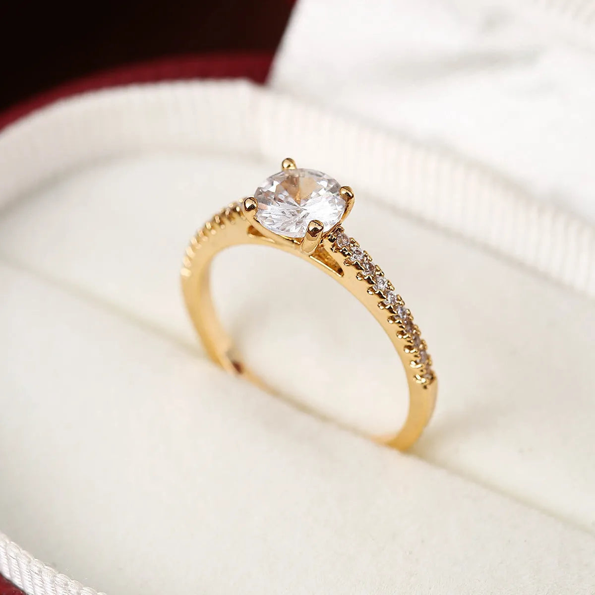 A hexagonal geometric ring with a zircon stone, shown in a gun black and rose red electroplated finish on a finger.