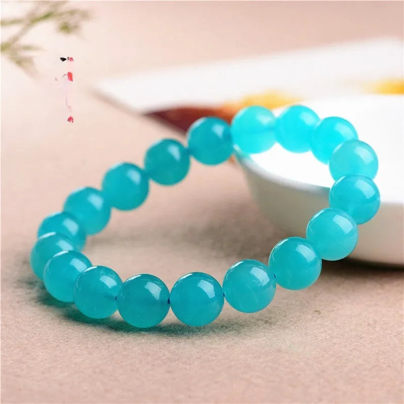 A selection of loose, polished ice-blue Amazonite beads in various sizes next to a finished crystal bracelet.