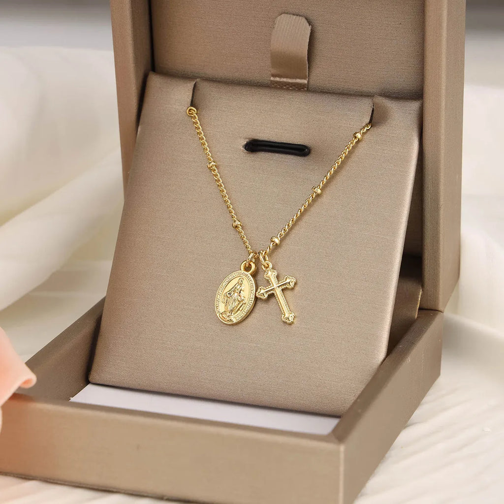 Geometric Virgin Mary cross pendant on a gold chain, showing simple design and 18K gold plating over copper.
