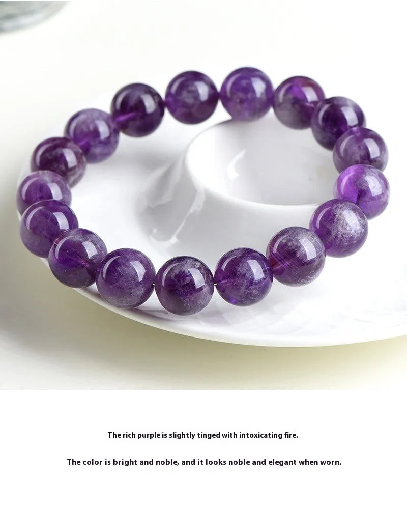 Natural feather amethyst crystal bracelet with scattered geometry beads and Ruyi element on a wrist.