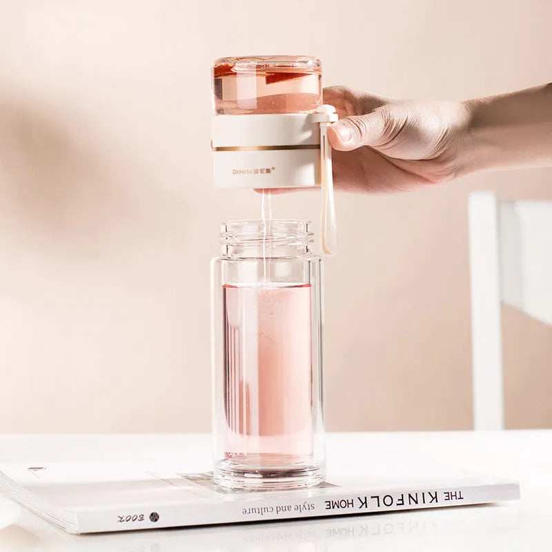 Green double-wall glass water bottle with a stainless steel tea infuser insert and a black leak-proof lid with rope handle.