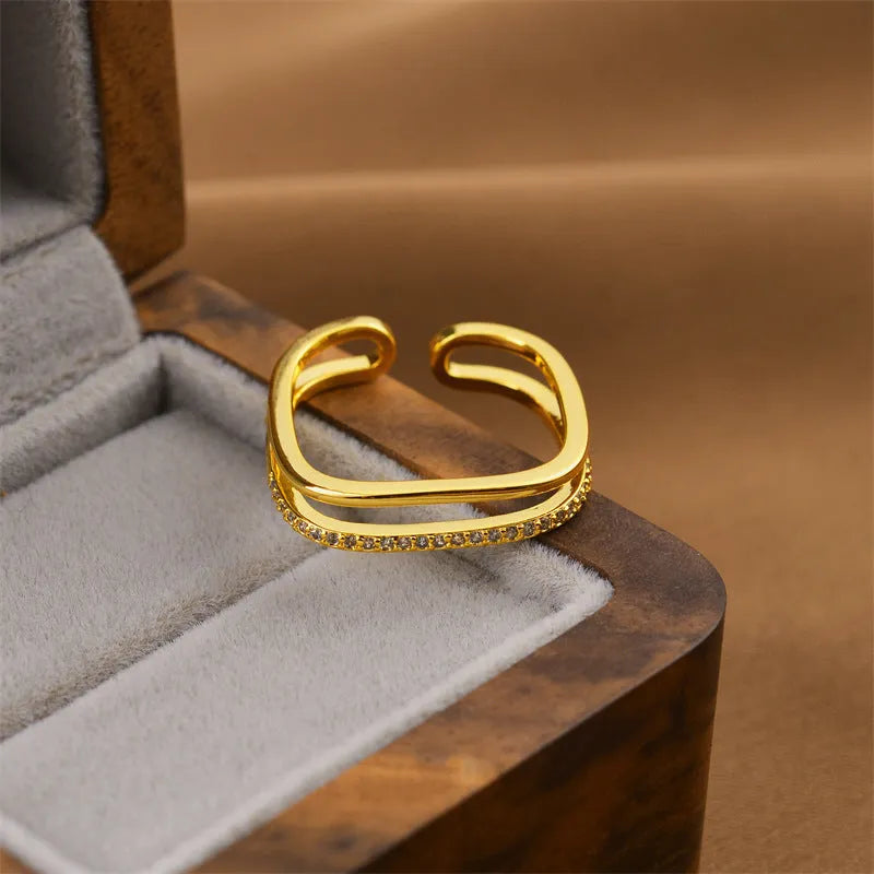Gold geometric open band women's fashion ring on a plain background.
