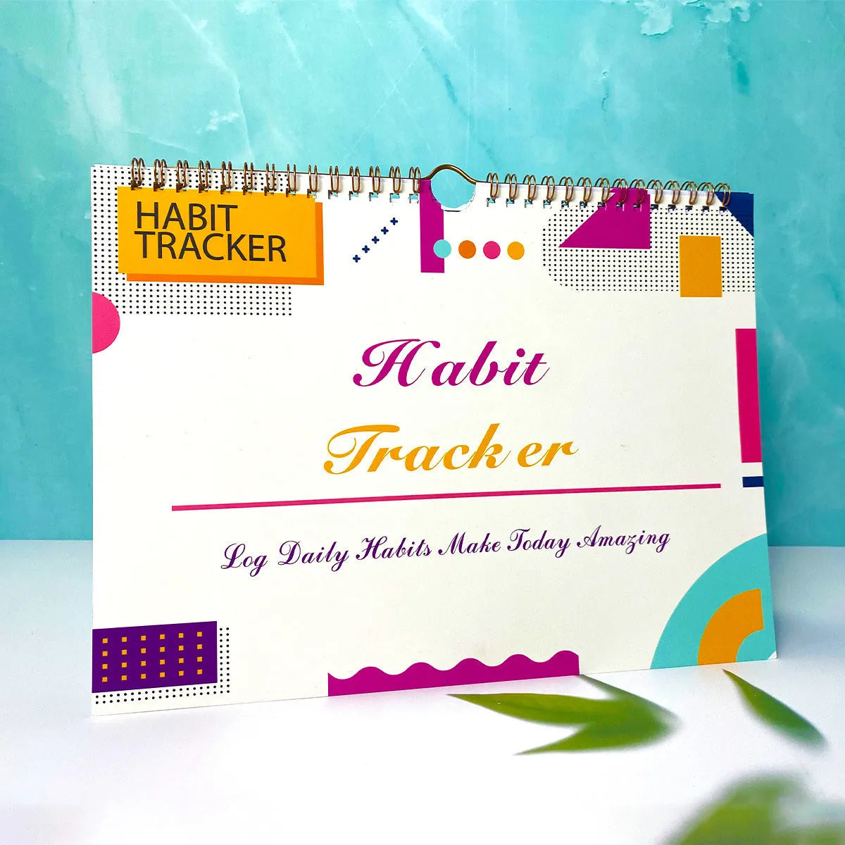 A5 habit tracking notebook open on a desk, showing internal pages, available in four colour options.
