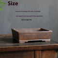 Rectangular purple sand bonsai pot with burnt pine tree decoration, shown on a garden surface.