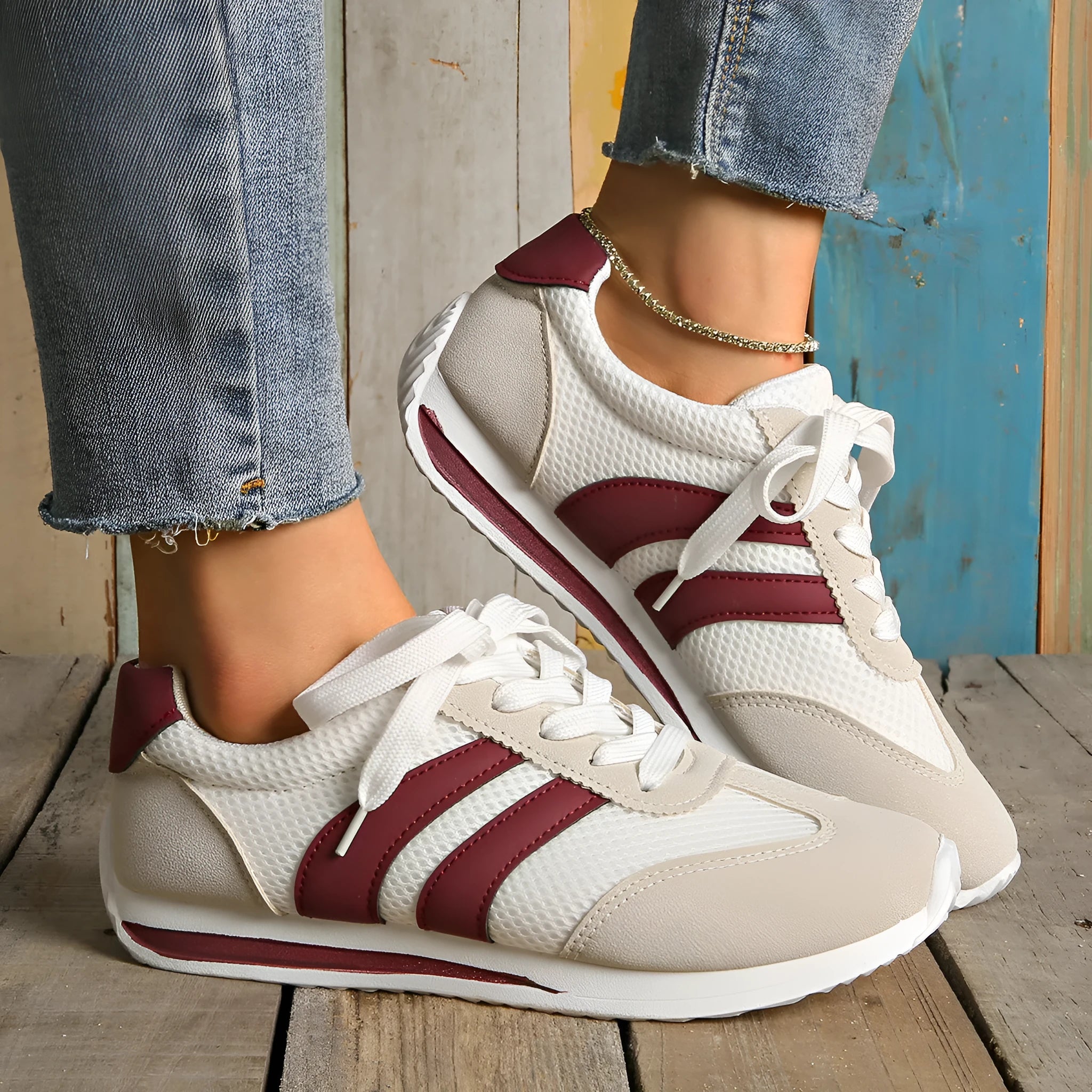 Wine red Cortez retro sneaker with cross straps, mesh lining, and flat rubber sole.