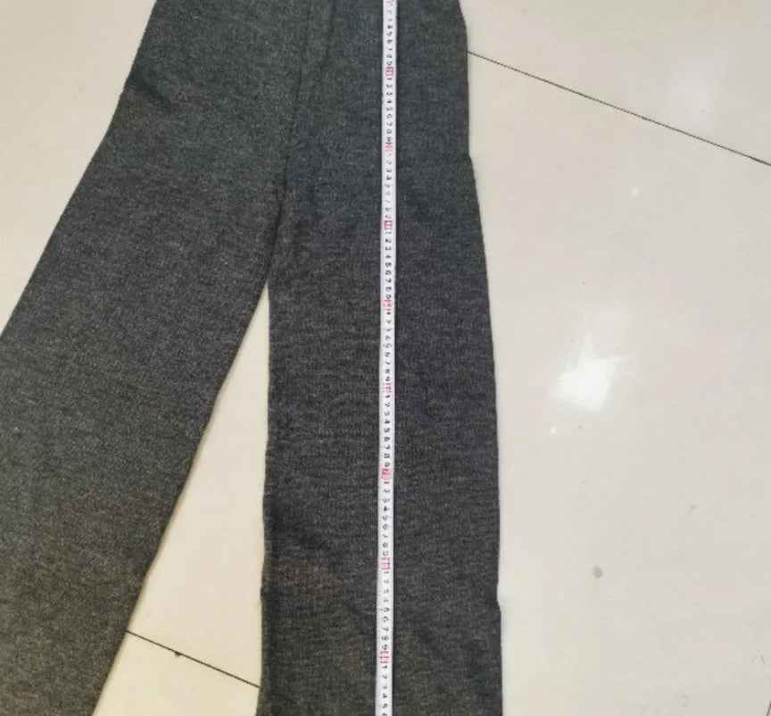 Women's dark grey acrylic knit suit with side-slit hem sweater and matching trousers laid flat.