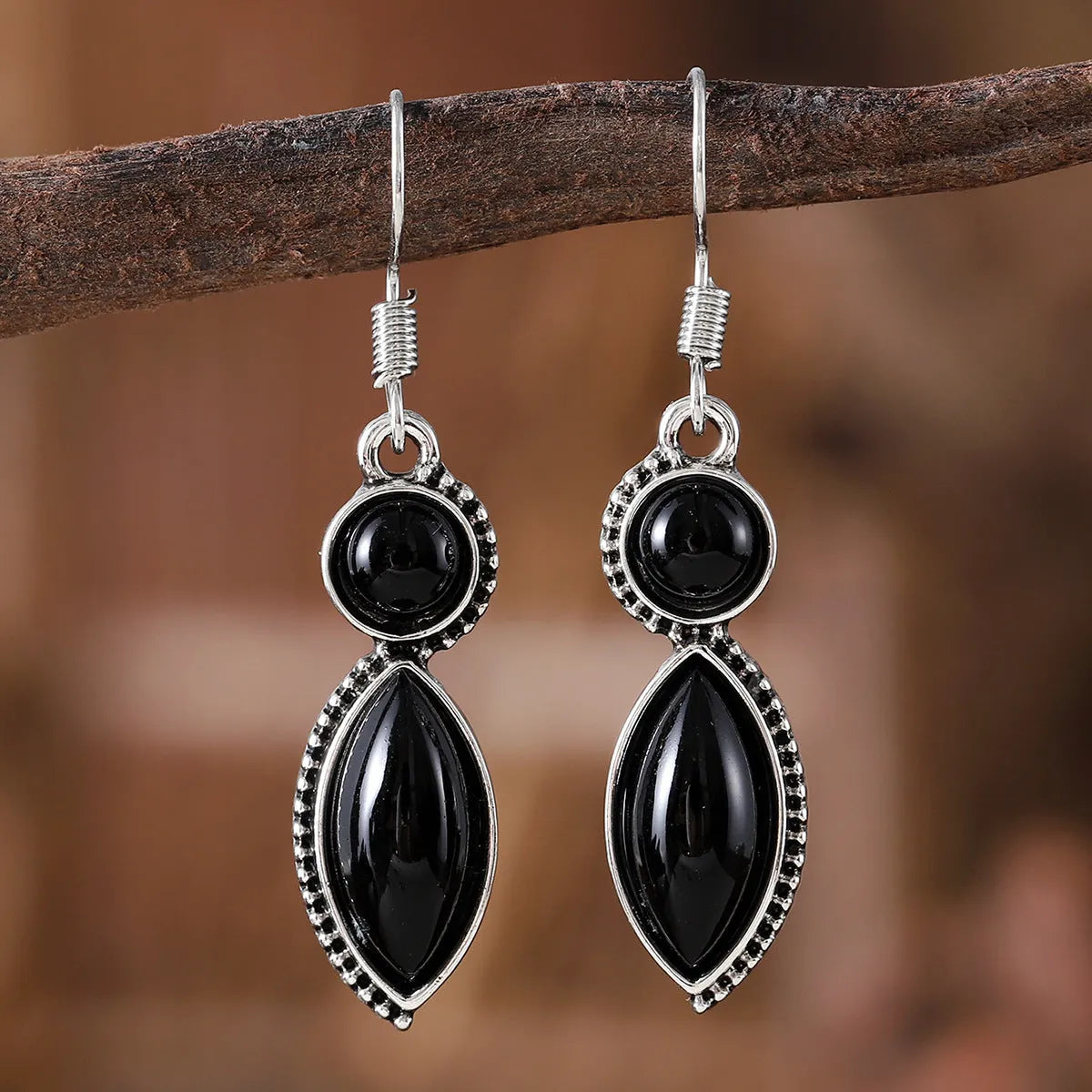 Vintage silver-tone geometric drop earrings with round purple and black stones on a grey background.