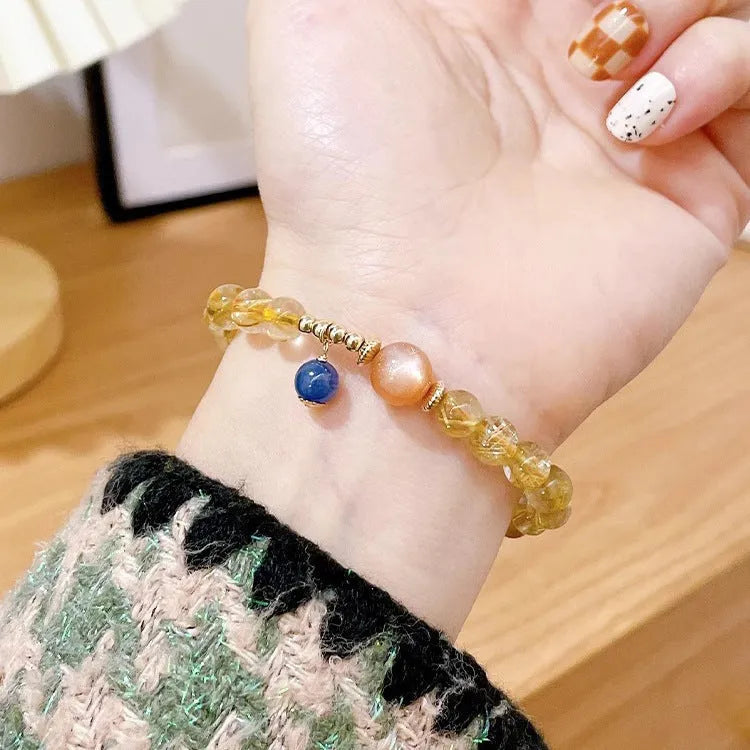 Gold rutilated quartz sunstone crystal bracelet with diamond-cut beads on wrist