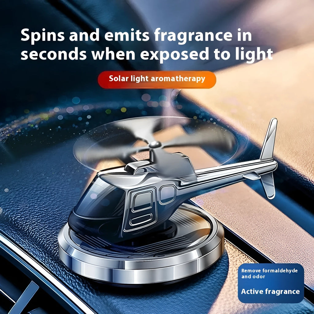 Silver metal solar-powered helicopter car air freshener spinning on a car dashboard