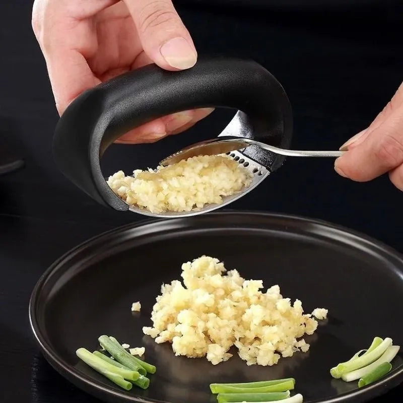 Stainless steel garlic press with ergonomic handle in assorted colours on a kitchen counter.