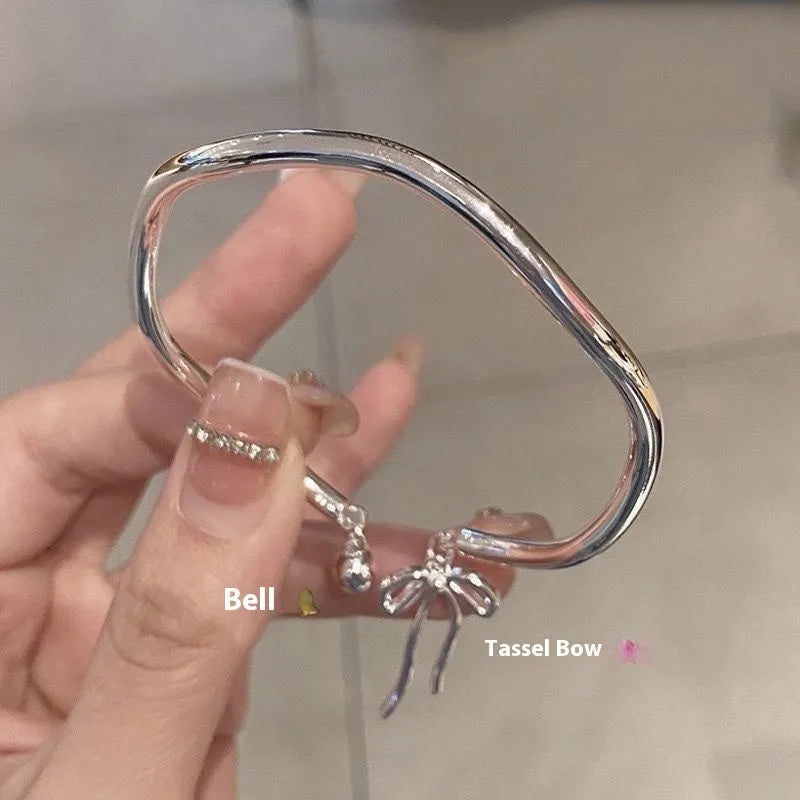 Silver adjustable bracelet with a large bow charm on a model's wrist, showing the sliding clasp.