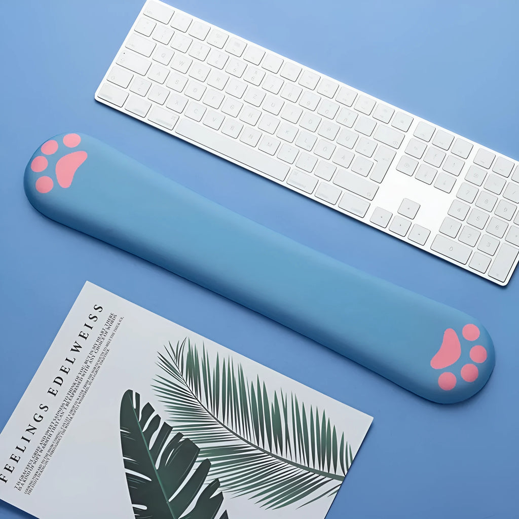 Blue memory foam keyboard wrist support pad on a wooden desk next to a keyboard.