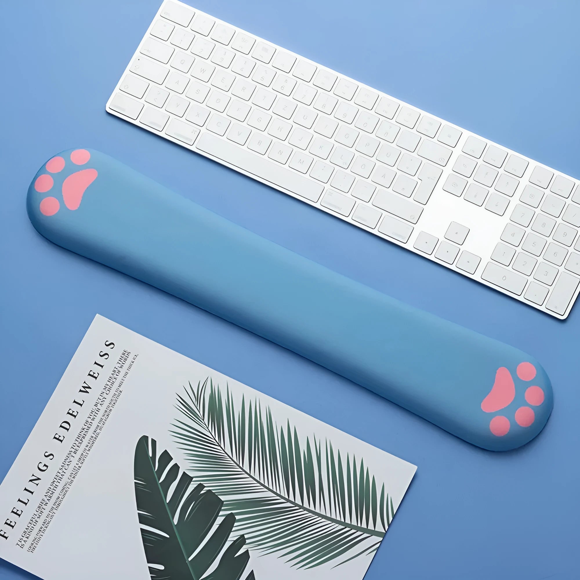 Blue memory foam keyboard wrist support pad on a wooden desk next to a keyboard.
