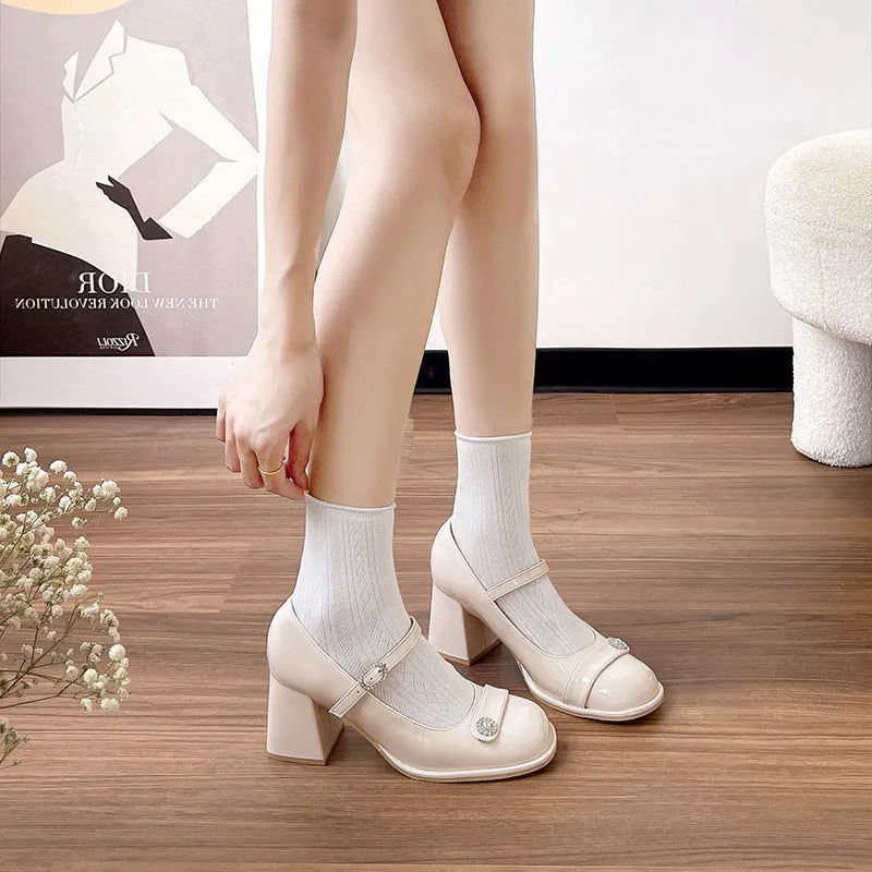 Women's black patent leather wide fit court shoes with a round toe and chunky buckle fastening heel.