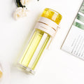 Green double-wall glass water bottle with a stainless steel tea infuser insert and a black leak-proof lid with rope handle.