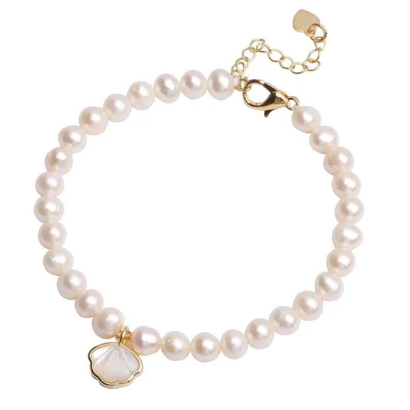 Women's freshwater pearl bracelet with a fan-shaped shell clasp on a wrist.