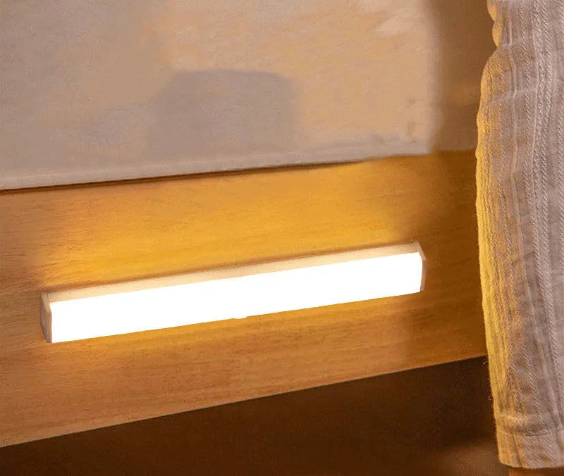 Black battery-powered LED strip light with motion sensor for cabinet or staircase installation.