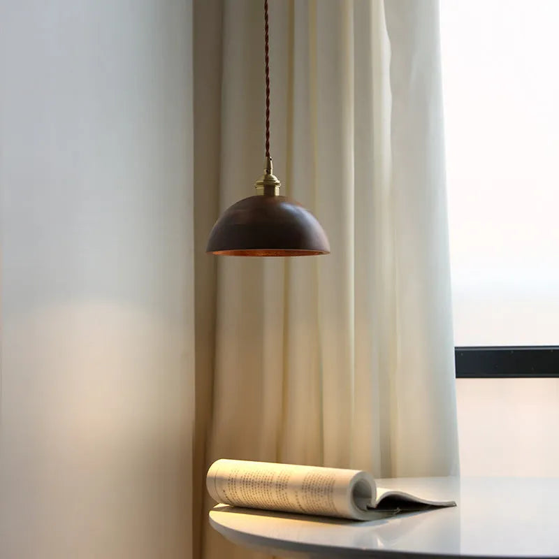 Black walnut and copper single-head droplight chandelier suspended from a ceiling.