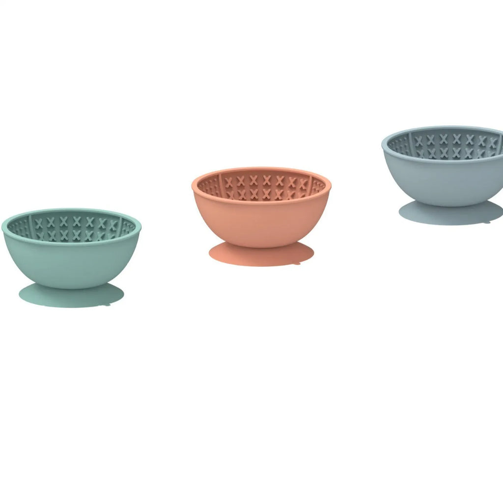 Cyan silicone dog bowl with textured slow-feed surface and a suction cup base on a kitchen floor.