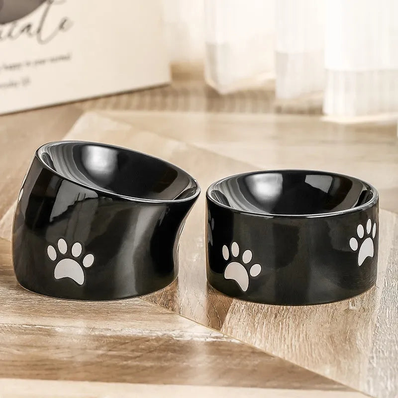 Ceramic cat food bowl with high foot base in a cat's paw print design