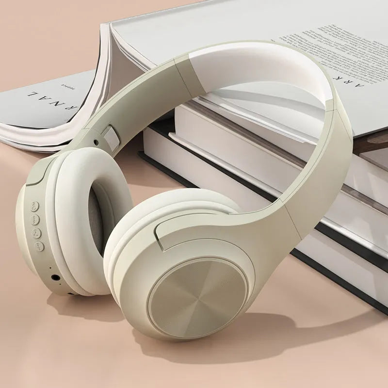 Over-ear wireless Bluetooth headset in Ivory White with a matching charging case on a table.