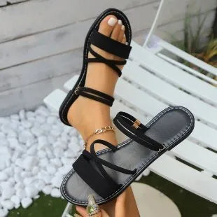Plus-size women's sandals with a black flip-toe buckle and cross-strap on a flat rubber sole.