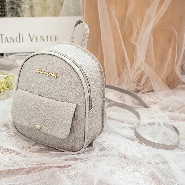 Compact black PU leather women's shoulder backpack worn crossbody, showing zipper closure and simple design.