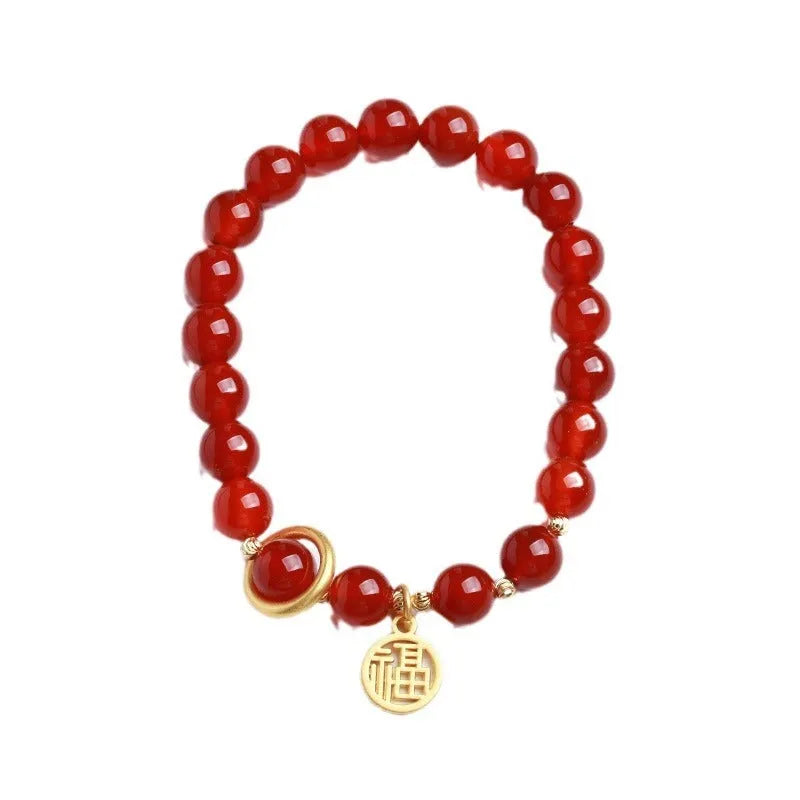 Close-up of a red agate beaded bracelet with woven design and a paper blessing card.
