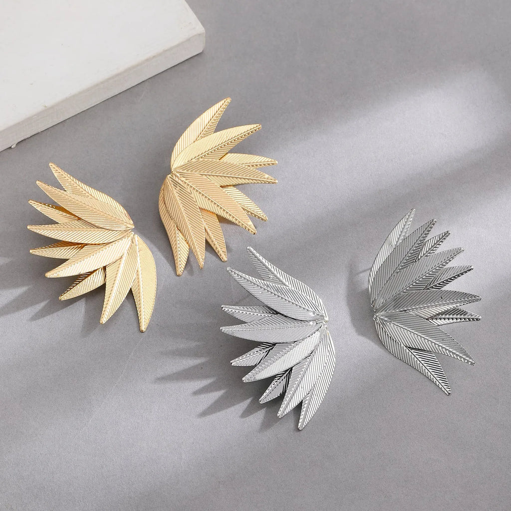 Gold and white alloy leaf shape patch earrings on a flat surface