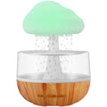 White cloud-shaped humidifier and essential oil diffuser with coloured mood light on.
