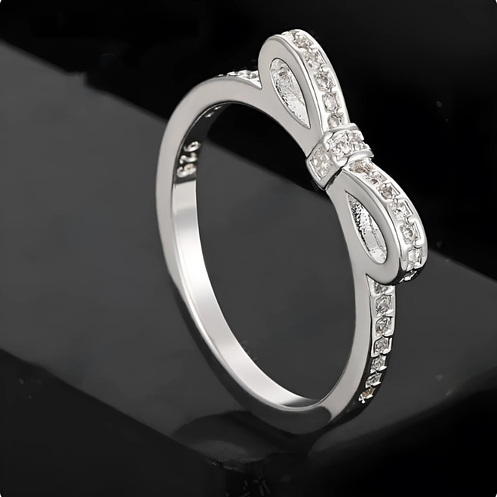 Silver electroplated sterling silver ring with a wide bow design set with clear zircon crystals.
