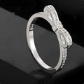 Silver electroplated sterling silver ring with a wide bow design set with clear zircon crystals.