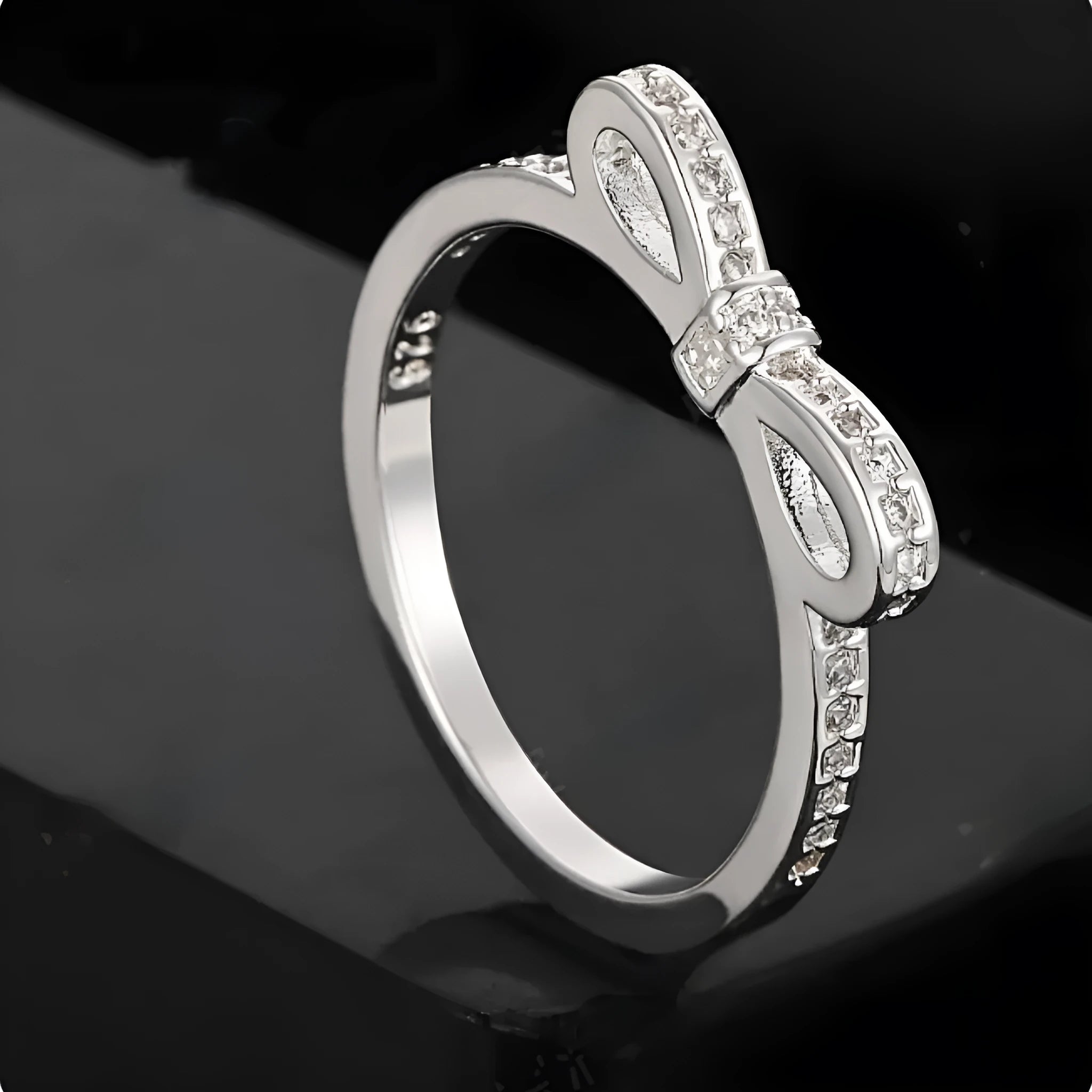 Silver electroplated sterling silver ring with a wide bow design set with clear zircon crystals.