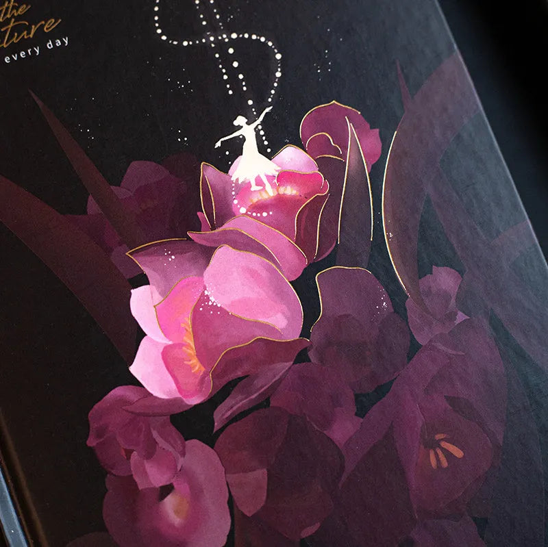 A5 notebook with a luminous cover shown in deep blue, open to reveal pages with colour illustrations.