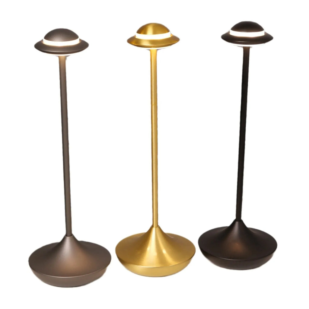 Modern gold UFO-shaped metal desk lamp with touch-sensitive base on a wooden table.
