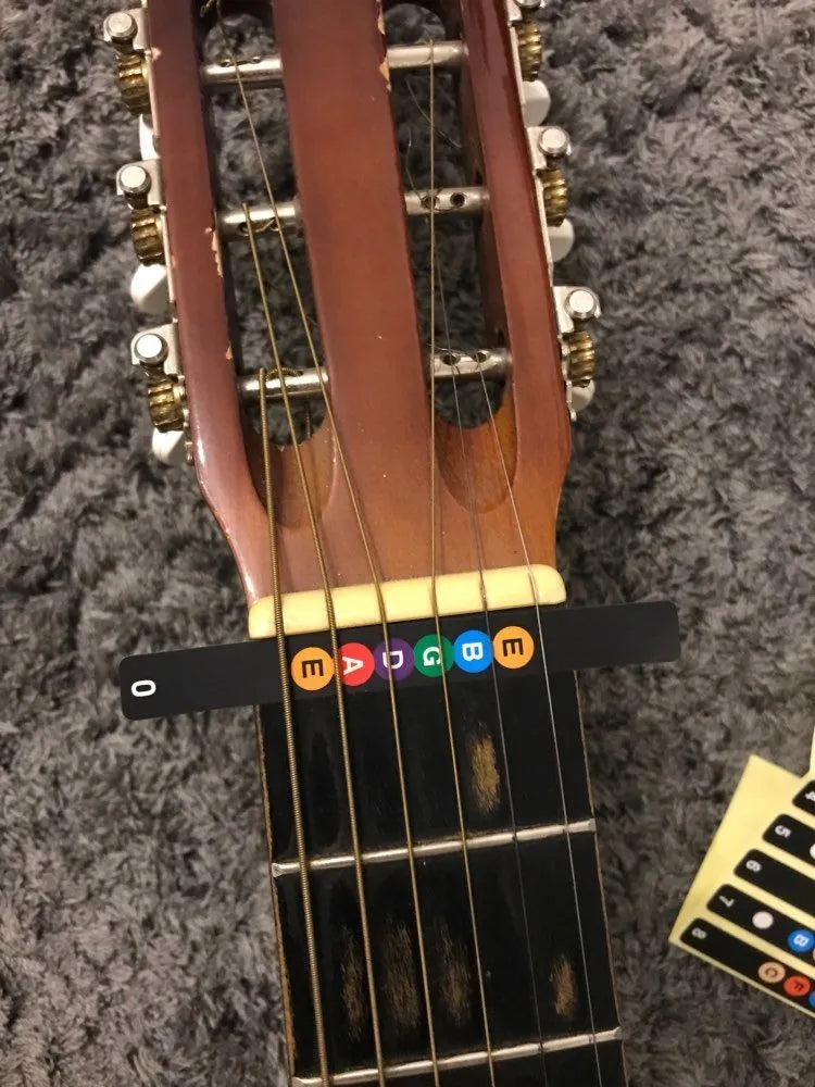Guitar fretboard note stickers on acoustic guitar fingerboard showing note labels