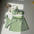 Women's light green one-shoulder swimsuit top with matching briefs and skirt on a hanger.