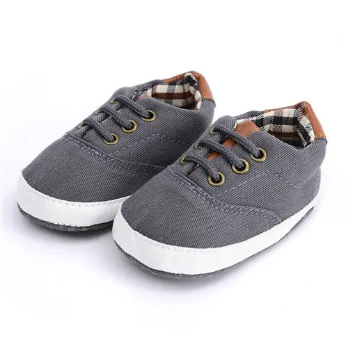 Solid colour baby canvas shoes with a front strap, shown in light grey on a white background.