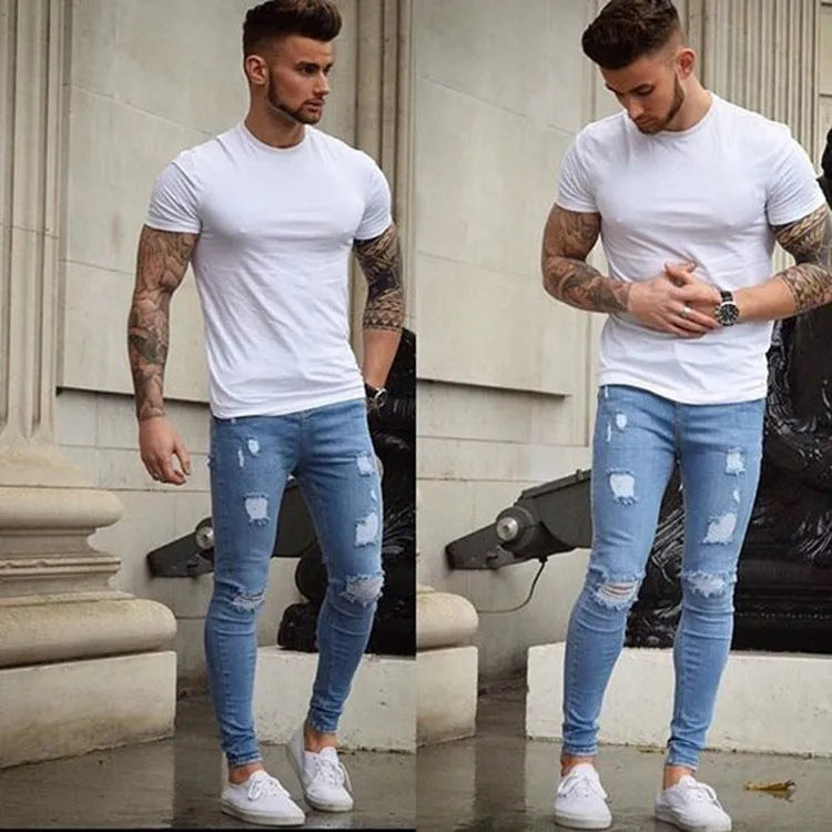 Frayed slim-fit jeans in blue, showing distressed hem and slim leg shape, on a model standing casually