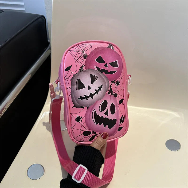 Black Halloween crossbody bag with orange pumpkin, white ghost, and bat graffiti print, shown worn across the body.