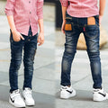 Boy wearing dark blue stretch denim jeans with zipper pockets, size chart shown