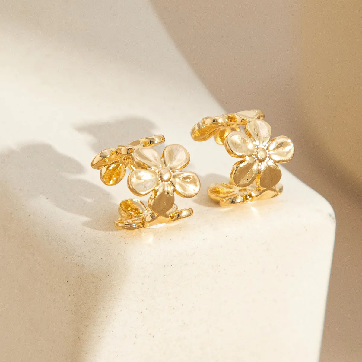 Gold coloured starfish and conch drop earrings on a white background.
