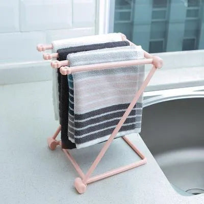 Light grey foldable plastic dishcloth shelf mounted on a wall holding towels.