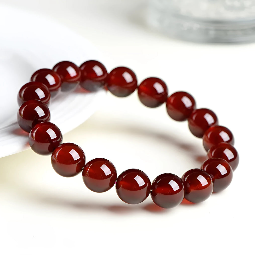 Natural orange red garnet crystal bracelet with ruyi design on a wrist.