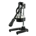 Black cast iron manual citrus juicer with stainless steel funnel on a kitchen counter.