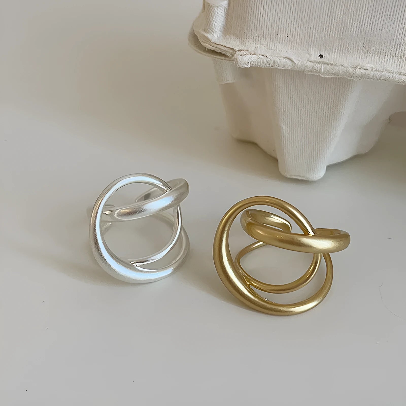 Geometric open ring with interlaced matte metal design in gold or silver plating.