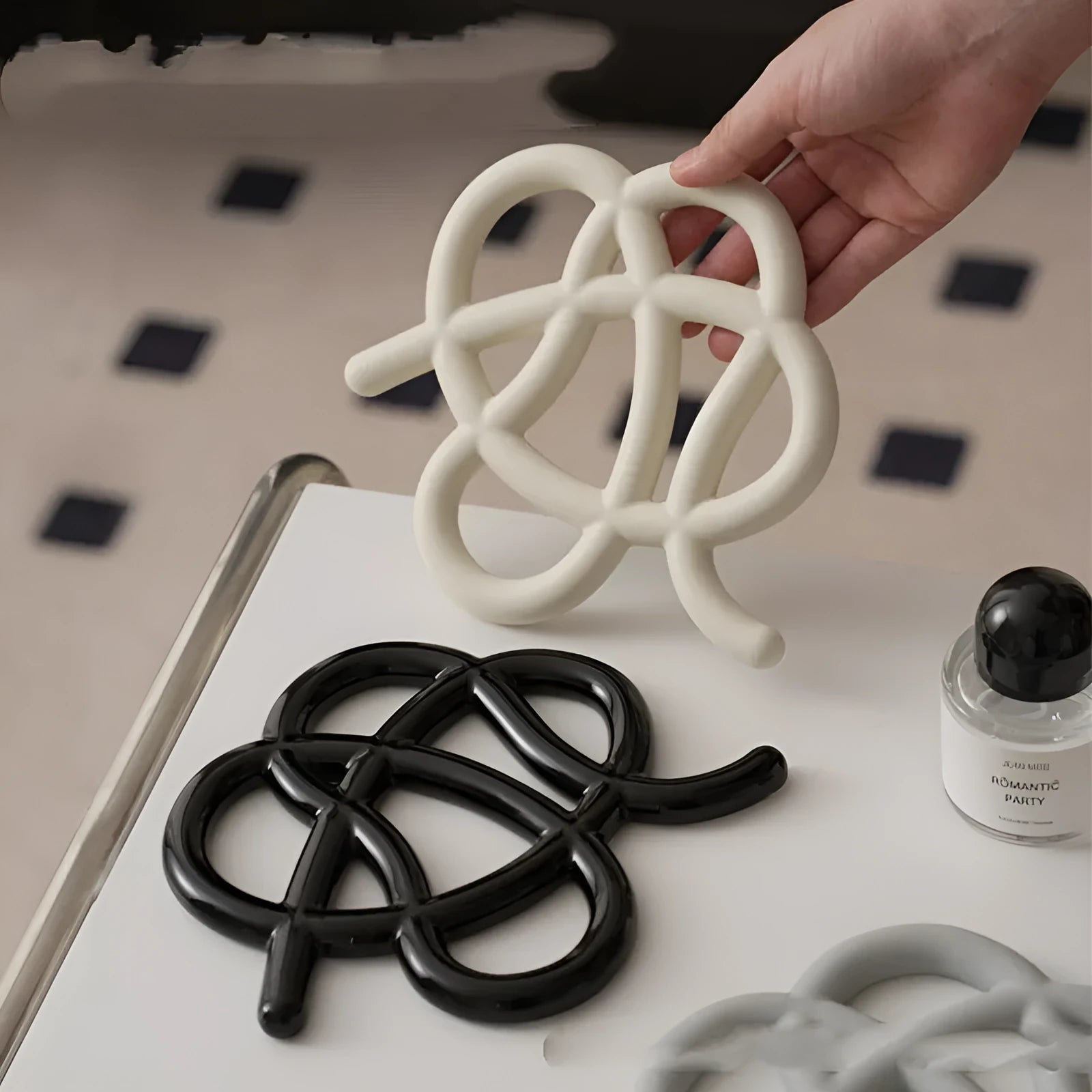 Modern irregular-shaped ceramic heat proof mat in grey protecting a wooden dining table from a hot pan.
