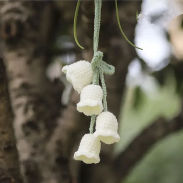 Green and white knitted wool car plant ornament hanging from a rope