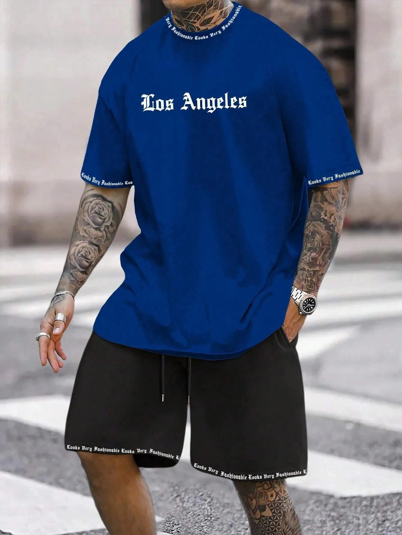 Man wearing a blue short-sleeved top and matching shorts from a sports style suit set.
