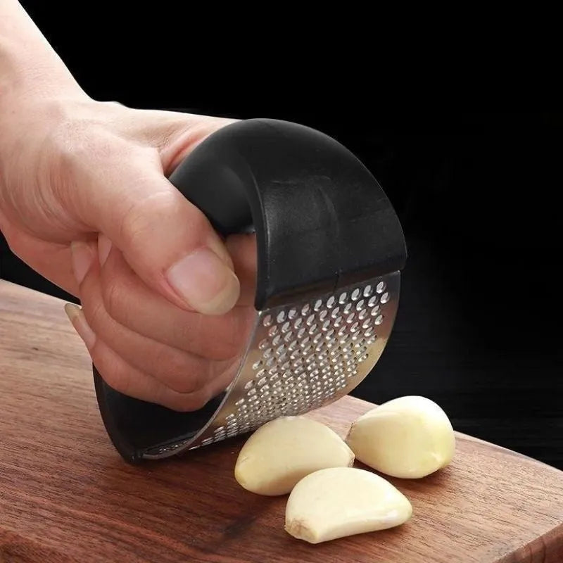 Stainless steel garlic press with ergonomic handle in assorted colours on a kitchen counter.